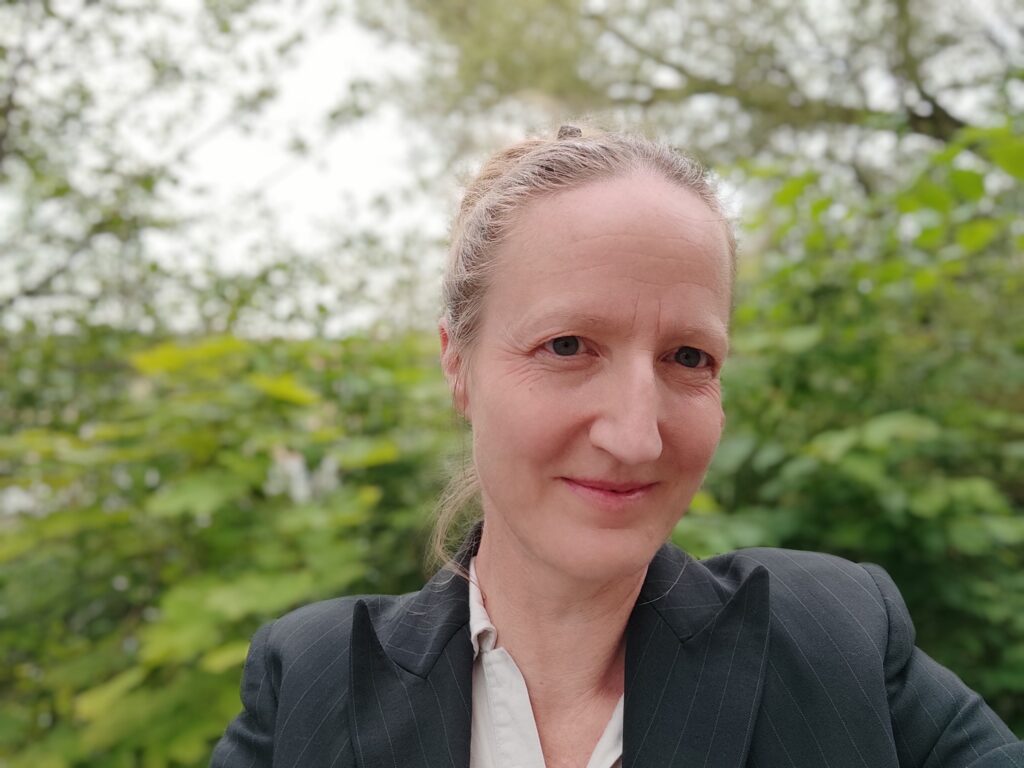 En kvinna med uppsatt hår, vit skjorta och svart kavaj