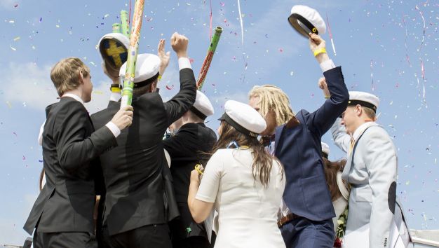 En grupp studenter med mössorna i vädret.