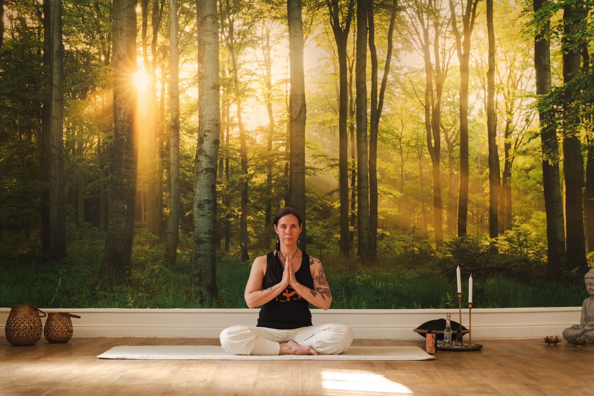 En kvinna i yogaställning framför en vägg med en skog på.